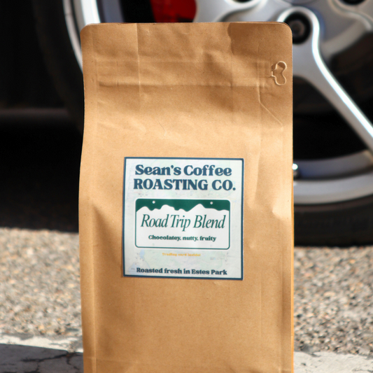 Brown coffee bag with a label on a road next to a car wheel